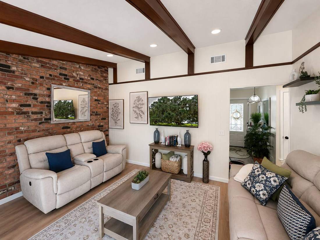 Living room with exposed brick wall, wood beams and reclining sofas